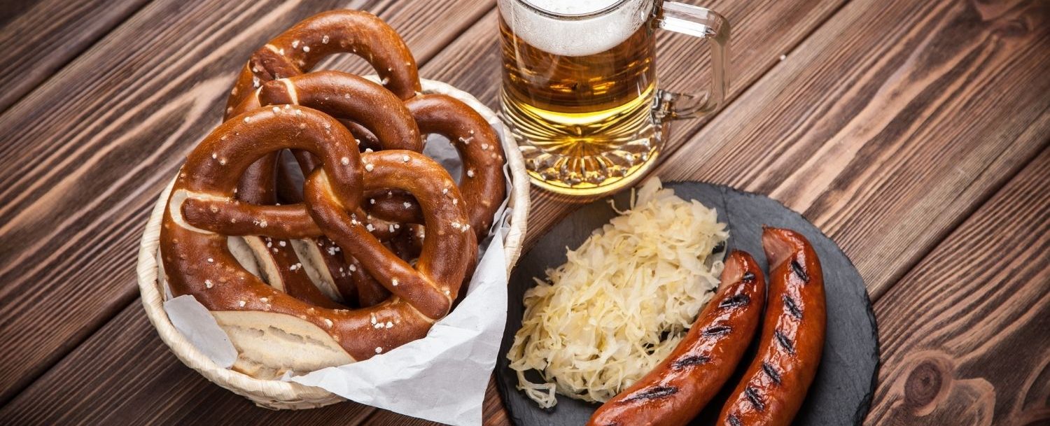 Pretzels, sausage, and beer on a table.